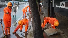Petugas PPSU membersihkan saluran air yang tersumbat di Jalan Mampang Prapatan Raya, Jakarta, Rabu (11/12/2019). Hal tersebut dilakukan guna mengurangi genangan air yang terjadi di sejumlah sudut Ibukota setiap kali hujan deras mengguyur Jakarta. (Liputan6.com/Immanuel Antonius)