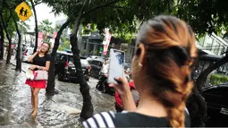 Seorang warga berfoto di tengah banjir yang melanda kawasan Kemang, Jakarta, Selasa (4/10). Hujan deras yang mengguyur Jakarta kembali menyebabkan kawasan Kemang tergenang air hingga setinggi 40 cm (Liputan6.com/Gempur M Surya)