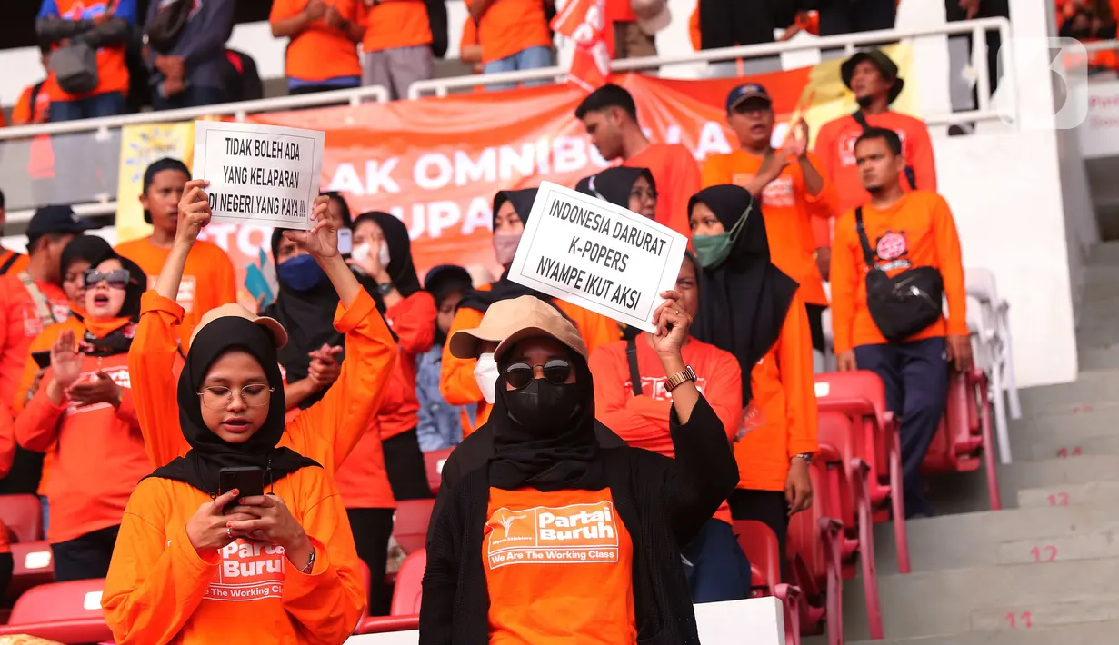 Sejumlah buruh membawa poster saat mengikuti aksi bertajuk May Day Fiesta 2022 di Stadion Gelora Bung Karno (GBK), Senayan, Jakarta Pusat, Sabtu (14/5/2022). Dalam aksi kali ini, massa buruh membawa 18 tuntutan, di antaranya menolak omnibus law UU Cipta Kerja, wujudkan kedaulatan pangan dan dan menolak kenaikan Pajak Pertambahan Nilai (PPN). (Liputan6.com/Angga Yuniar)