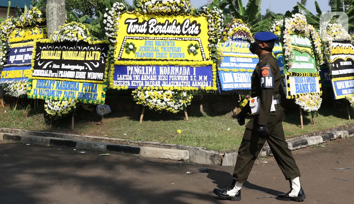 Prajurit TNI melintas di depan karangan bunga tanda duka cita atas meninggalnya mantan KSAD Jenderal TNI (Purn) Pramono Edhie Wibowo di kawasan Puri Cikeas, Kab Bogor, Jabar, Minggu (14/6/2020). Pramono Edhie Wibowo wafat di usia 65 tahun akibat serangan jantung. (Liputan6.com/Helmi Fithriansyah)