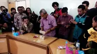 Istri terduga teroris Sriyono yang tewas setelah berduel dengan anggota Densus, menyerahkan barang bukti dua bungkus uang ke Kantor PP Muhammadiyah, Yogyakarta. (Liputan6.com/Fathi Mahmud) 
