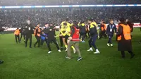 Pemain Fenerbahce diserang oleh pendukung Trabzonspor dalam pertandingan Liga Super Turki di Papara Park, Minggu (17/3/2024) (DHA (Demiroren News Agency) / AFP)