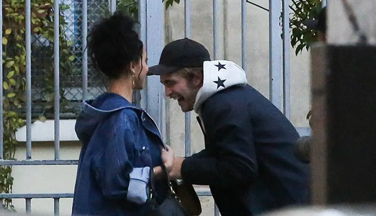 Mengenakan topi dan jaket Robert Pattinson tertawa ceria saat bercanda dengan FKA Twigs, Paris, (15/10/14). (Dailymail)