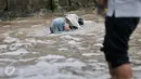 Seorang wanita terperosok ke dalam lubang saat melintasi banjir di Jalan Taman Bukit Duri, Jakarta Selatan, Selasa (21/2). Banjir yang menutupi jalan membuat lubang tak terlihat. (Liputan6.com/Yoppy Renato)