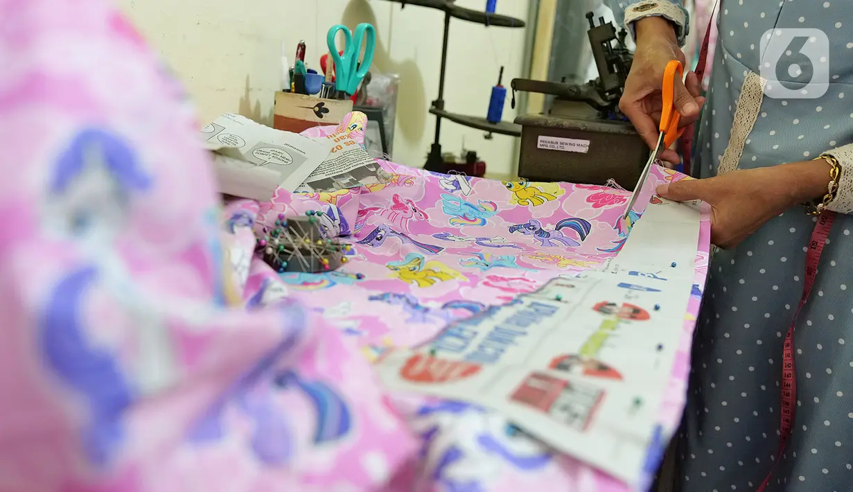 Penjahit sedang membuat pola penutup kepala di kawasan Cipinang Cempedak, Jakarta, Kamis (18/6/2020). Kreasi penutup kepala, masker dan Gown yang di inisiasi oleh seorang dokter di RSIA Tambak yang di design untuk khusus tema anak saat masa Pandemi  COVID-19. (Liputan6.com/Herman Zakharia)