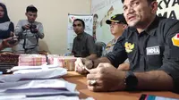 Ketua Bawaslu Pekanbaru Indra Kholid dengan uang diduga untuk serangan fajar di meja hasil tangkapan anggotanya. (M Syukur/Liputan6.com)