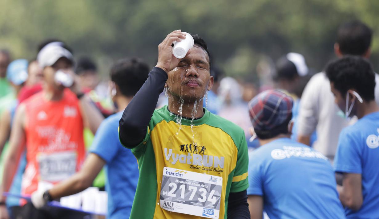 Seorang pelari mengguyur wajahnya dengan air saat mengikuti Mandiri Jakarta Marathon. (Bola.com/Vitalis Yogi Trisna)
