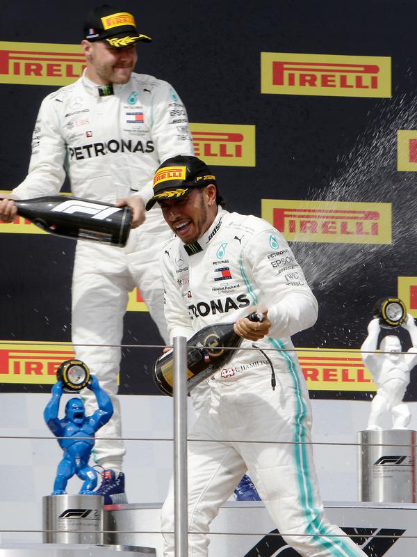 Pebalap Mercedes Lewis Hamilton (kanan) dan Valtteri Bottas berselebrasi dengan menyemprotkan sampanye saat menjuarai F1 GP Prancis 2019 di Sirkuit Paul Ricard, Minggu (23/6/2019). Hamilton tampil dominan dan menjadi juara F1 GP Prancis 2019. (AP Photo/Claude Paris)