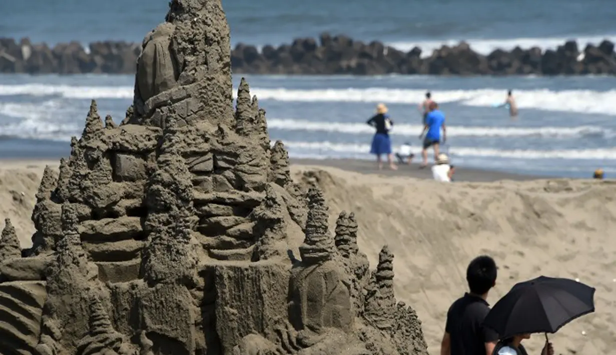 Pengunjung sedang menikmati pemandangan pantai diantara patung pasir di Yasashigaura, Pantai Asahi , Tokyo, Sabtu (11/7/2015). Pameran ini digelar mulai Senin (6/7) lalu. (AFP PHOTO/Toshifumi Kitamura)