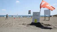 Bendera merah dikibarkan di tepi pantai di Hiratsuka, Prefektur Kanagawa, usai pemerintah mengumumkan 'peringatan gempa besar' di Jepang. (dok. STR / JIJI Press / AFP)