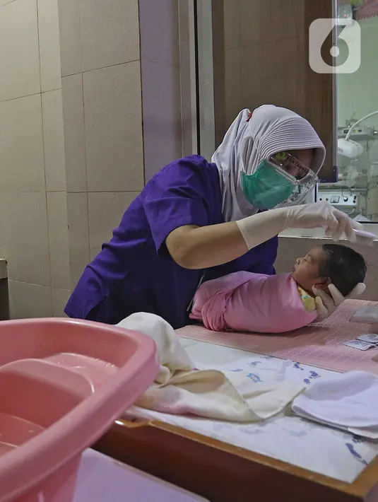 Perawat merapikan rambut seorang bayi setelah dimandikan saat kegiatan pelatihan di RSIA Tambak, Jakarta, Kamis (18/02/2021). Melatih para ibu baru untuk memandikan bayi pertama tersebut dilakukan dengan menerapkan protokol kesehatan ketat. (Liputan6.com/Herman Zakharia)