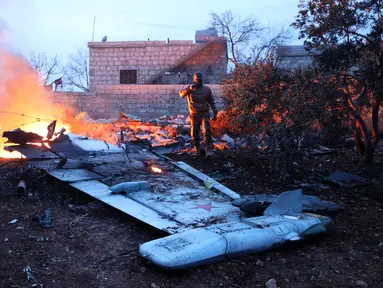 Seorang militan Suriah mengambil gambar jet tempur Sukhoi-25 milik Rusia yang jatuh di provinsi Idlib, Suriah (3/2). Menurut laporan lembaga Observasi HAM Suriah, jet tempur Rusia itu ditembak jatuh pada Sabtu sore. (AFP/Omar Haj Kadour)