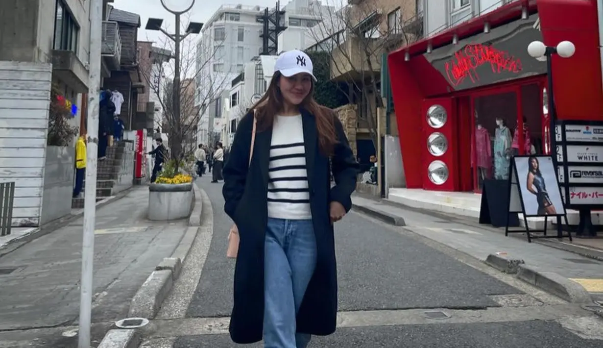 Aaliyah mengenakan coat hitam panjang dipadukan sweater putih sebagai inner dan celana denim. Ia memadukannya dengan topi cap MLB New York Yankees cap warna putih seharga Rp560 ribuan. Serasi dengan sepatu putih Samba OG seharga Rp2.2 jutaan.  [@aaliyah.massaid]