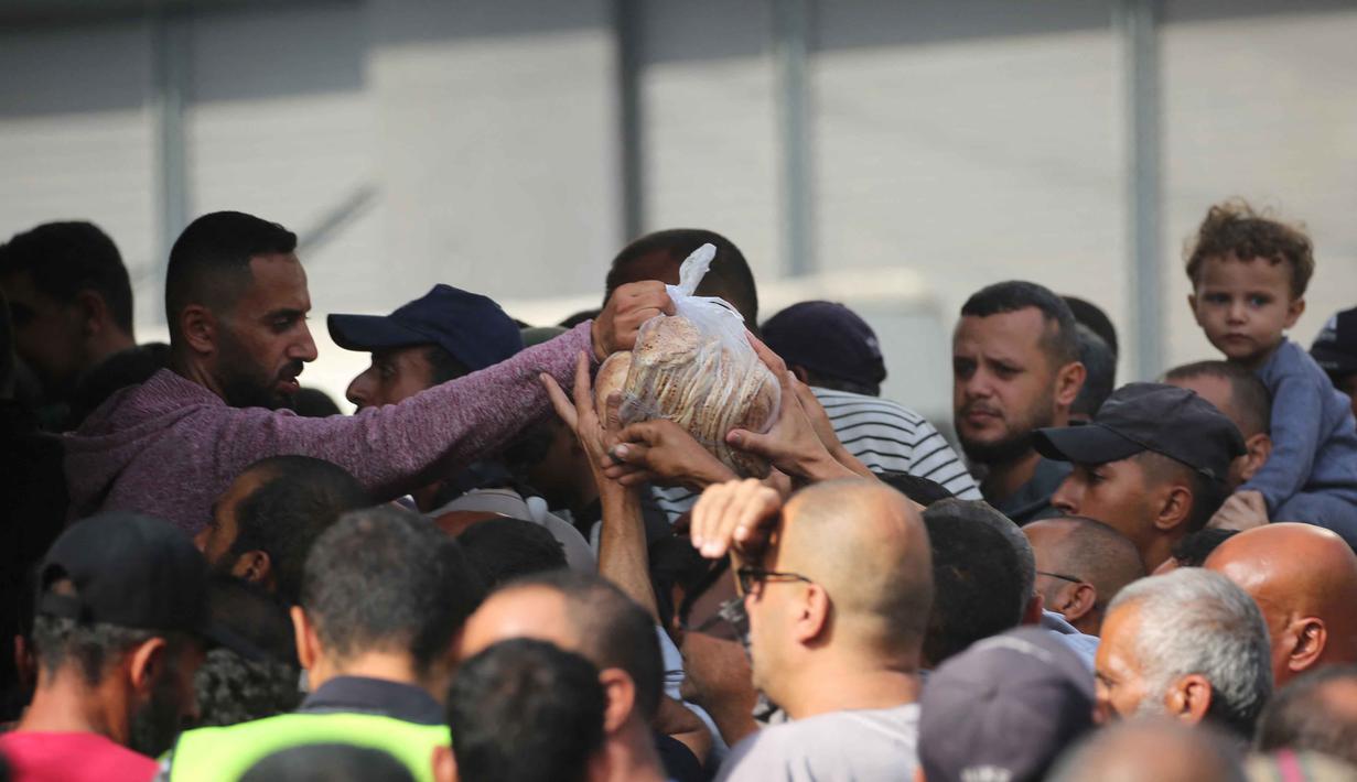Warga Palestina menerima sekantong roti dari toko roti amal di kamp pengungsi Nuseirat, yang terletak di Jalur Gaza tengah, pada 2 November 2025. Melalui mekanisme pengiriman 2720 yang disahkan oleh Dewan Keamanan PBB, bantuan terus disalurkan ke Gaza. (EYAD BABA/AFP)