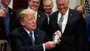 Presiden AS, Donald Trump memegang mainan Astronot setelah menandatangani sebuah kebijakan untuk mengirim astronot Amerika kembali ke bulan dan Mars di Ruang Roosevelt Gedung Putih di Washington (11/12). (AP Photo/Evan Vucci)