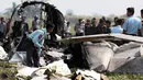 Petugas memeriksa puing pesawat militer yang jatuh sesaat setelah lepas landas di bandara Kota Naypidaw, Myanmar, Rabu (10/2). Pesawat penumpang jenis Beechcraft tersebut sedang membawa lima orang kru militer yang akan melakukan patroli rutin. (STR/AFP)