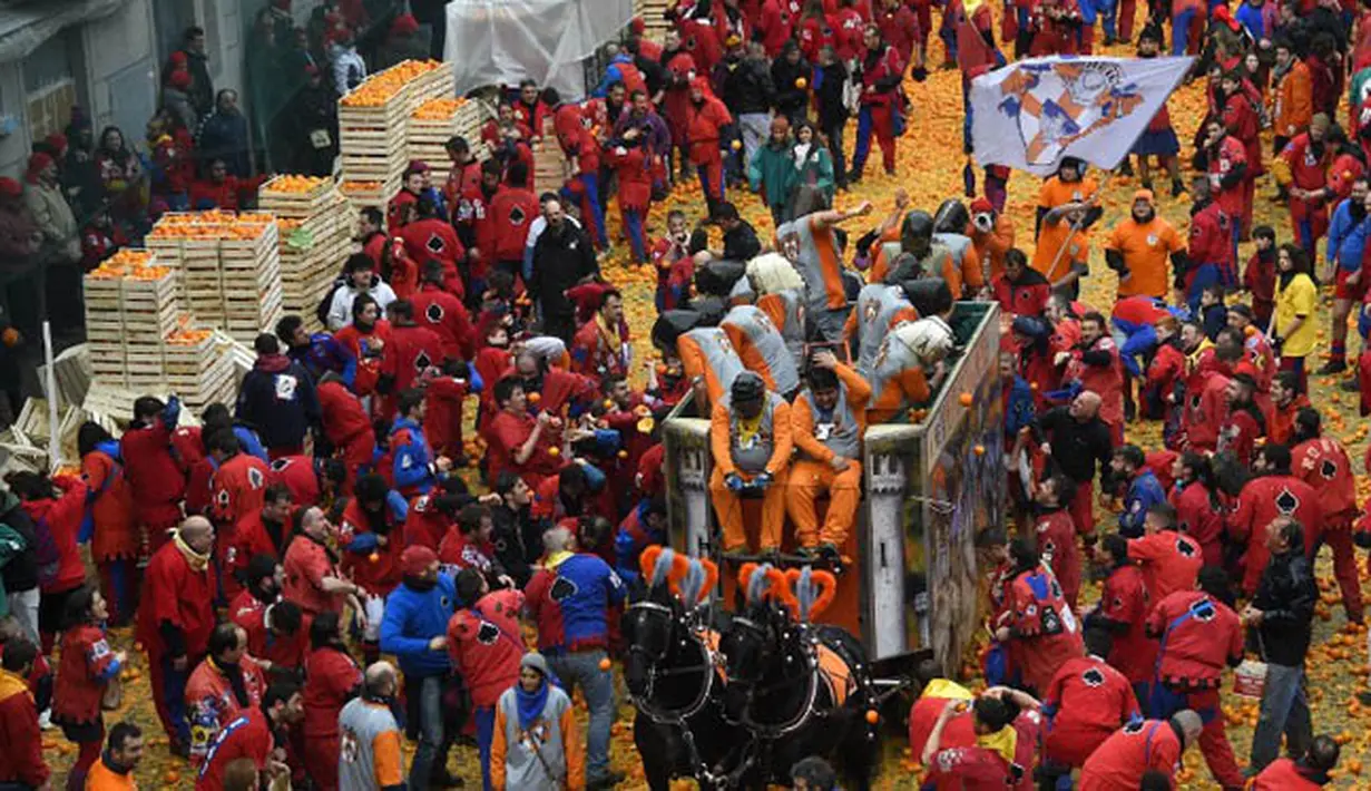 Sekelompok warga turut ambil bagian dalam perang jeruk yang diselenggarakan selama Karnaval Ivrea di Turin, Italia (16/2). (AFP PHOTO/Olivier MORIN)