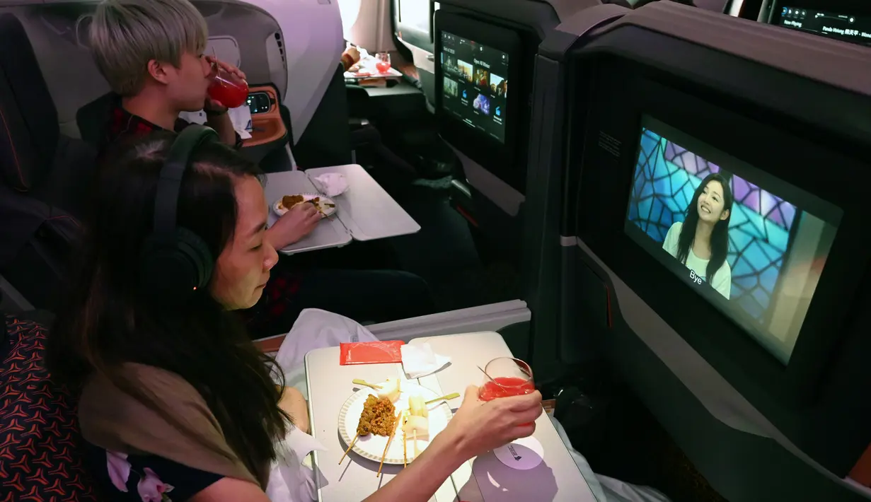 Pengunjung menonton film sembari menikmati makanan di kelas bisnis selama makan siang perdana di Restaurant A380 @Changi di atas pesawat Airbus A380, di Bandara Internasional Changi, 24 Oktober 2020. Singapore Airlines mengubah salah satu pesawatnya menjadi sebuah restoran mewah. (ROSLAN RAHMAN/AFP)