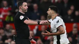 Pemain Fulham, Aleksandar Mitrovic (kanan), mendorong wasit Chris Kavanagh setelah memberikan kartu merah kepada Willian yang menghalau bola menggunakan tangannya untuk mencegah gawang timnya kebobolan dalam babak perempat final Piala FA 2022/2023 melawan Manchester United yang berlangsung di Old Trafford, Minggu (19/3/2023) malam WIB. (AFP/Paul Ellis)