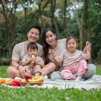 Keluarga bahagia sedang piknik di taman yang rindang, menikmati akhir pekan bersama. (Depositphoto/BongkarnGraphic)