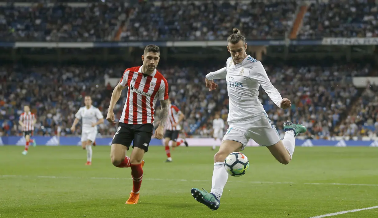 Aksi pemain Real Madrid, Gareth Bale (kanan) mencoba melewati adangan pemain Athletic Bilbao, Unai Nunez pada lanjutan La Liga Santander di Santiago Bernabeu stadium, Madrid, (18/4/2018). Real Madrid bermain imbang 1-1 dengan Bilbao. (AP/Francisco Seco)