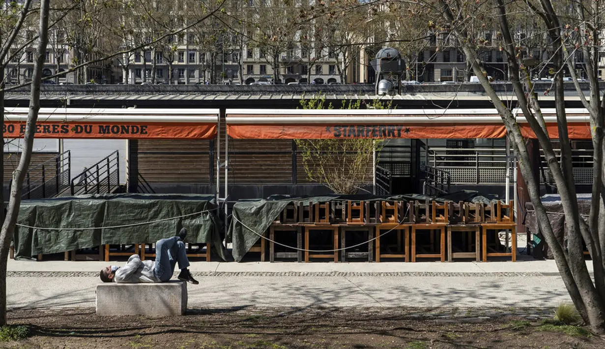 Seorang pria menikmati matahari di depan bar yang tutup di Lyon, Prancis, Kamis (1/4/2021). Prancis bersiap melakukan lockdown setelah pemerintah menemukan adanya lonjakan kasus COVID-19. (AP Photo/Laurent Cipriani)