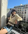 Momen Lisa di Paris, berpose di pinggir jendela kamar hotelnya dengan outfit bernuansa preppy. Kemeja cokelat ditumpuknya dengan sweater dan dipadu dengan mini skirt jeans. Di sini, ia mengenakan bucket hat hitam. Foto: Instagram.