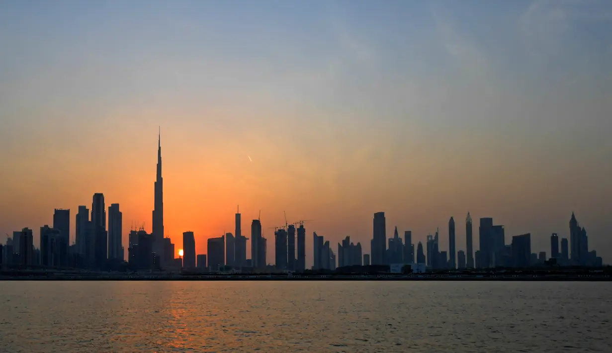 Matahari terbenam di belakang bangunan tertinggi di dunia Burj Khalifa dan gedung-gedung bertingkat lainnya, di Dubai, Uni Emirat Arab pada Sabtu (12/9/2020). (Photo by Karim SAHIB / AFP)