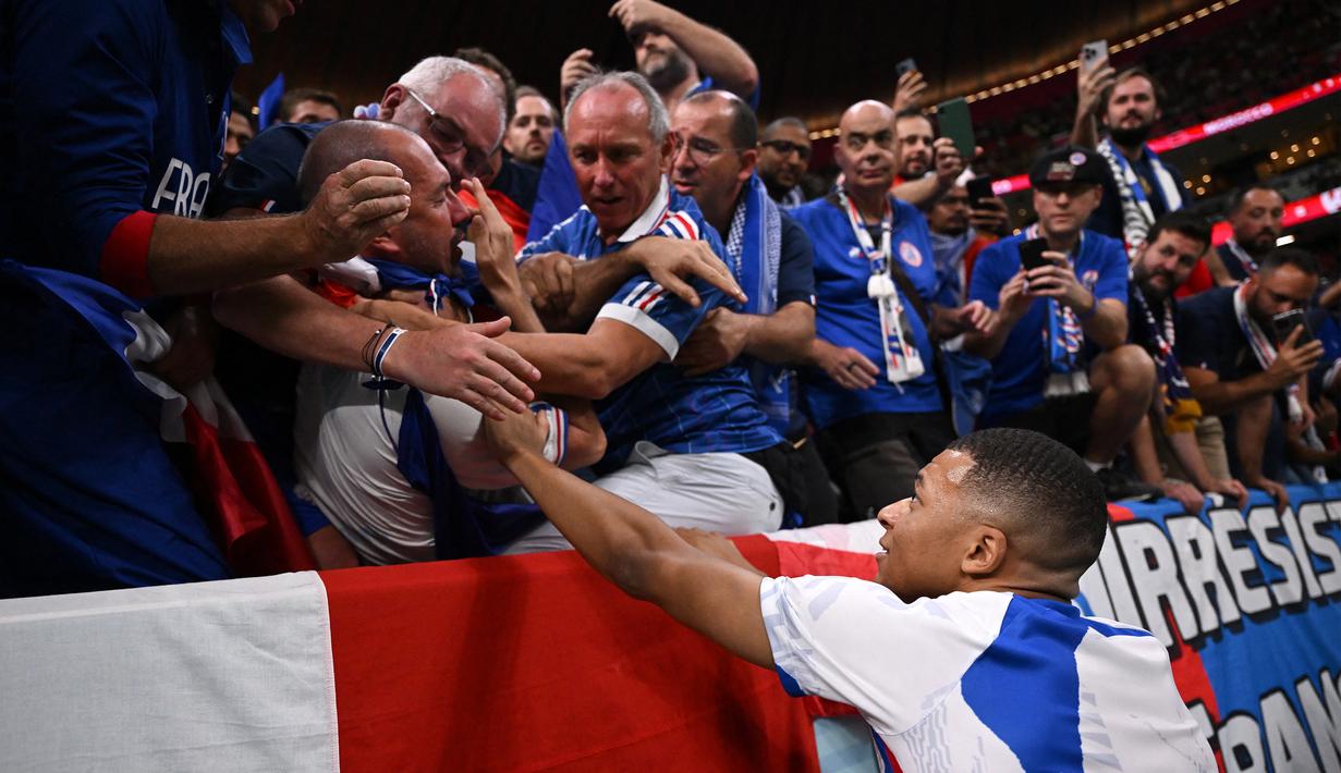 Ada kejadian memilukan yang dialami suporter Timnas Prancis sebelum pertandingan semifinal Piala Dunia 2022 dimulai. Kylian Mbappe yang sedang melakukan pemanasan tak sengaja melepaskan tembakan yang salah arah ke tribun hingga mengenai seorang suporter. (AFP/Kirill Kudryavtsev)