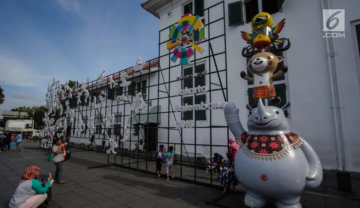 Pengunjung berfoto dekat ornamen Asian Games 2018 di kawasan Kota Tua, Jakarta, Senin (4/12). Ornamen tersebut untuk mengajak warga mensukseskan dan memeriahkan acara yang akan berlangsung pada 18 Agustus-2 September. (Liputan6.com/Faizal Fanani)