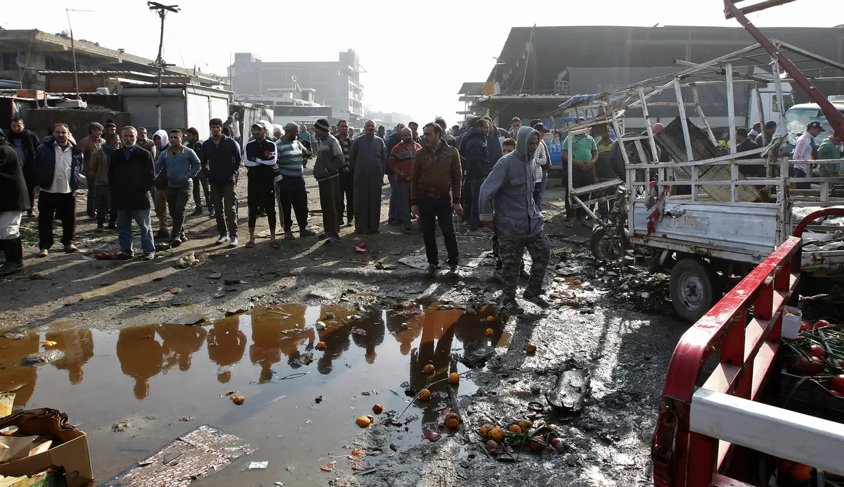 Warga berkumpul untuk melihat dan memeriksa sekitar lokasi ledakan di pasar sayur Jumila di Baghdad, Irak (8/1). Akibat ledakan bom tersebut, belasan orang dilaporkan tewas dan banyak lainnya menderita luka-luka. (AFP/Sabar Arar)