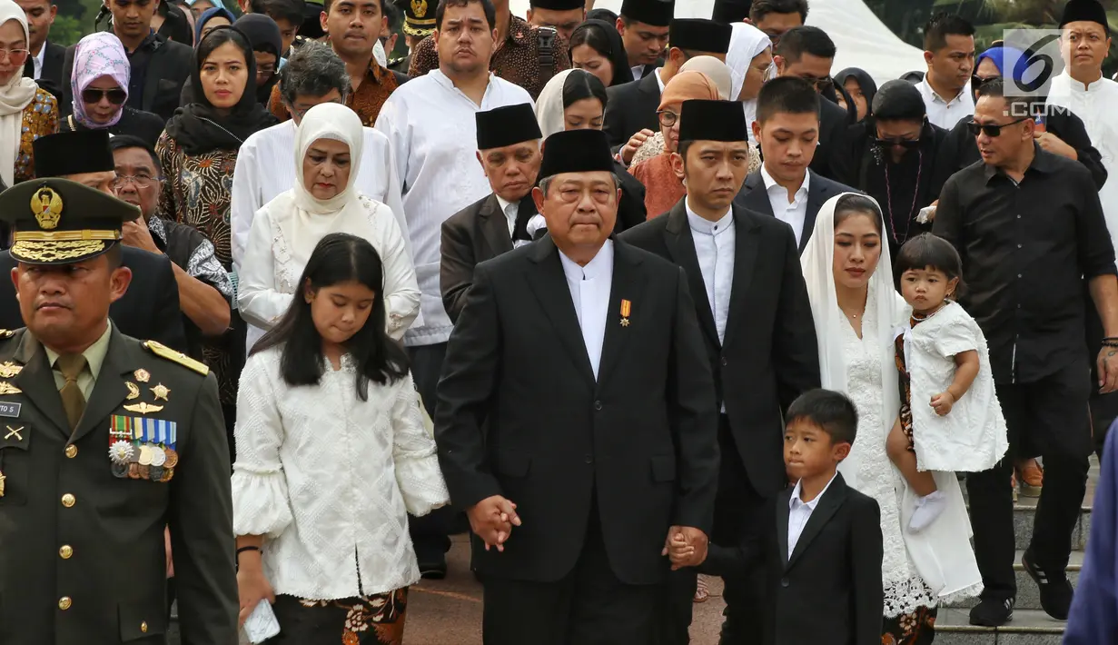 Presiden ke-6 RI Susilo Bambang Yudhoyono (SBY) menggandeng cucu-cucunya saat menghadiri pemakaman sang istri Ani Yudhoyono di TMP Kalibata, Jakarta, Minggu (2/6/2019). Ani Yudhoyono dimakamkan di samping pusara istri presiden ke-3 RI BJ Habibie, Ainun Habibie. (Liputan6.com/JohanTallo)