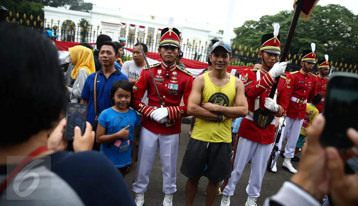 Warga berfoto bersama anggota Paspampres yang melakukan prosesi pergantian jaga Istana Kepresiden di depan Istana Merdeka, Minggu (28/8). Prosesi pergantian yang diwarnai sejumlah atraksi itu mengundang perhatian warga. (Liputan6.com/Faizal Fanani)