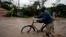 Seorang warga menuntun sepedanya saat melintasi banjir yang disebabkan oleh hantam Badai Matthew di Haiti (4/10). Keganasan Badai Matthew ini telah meluluhlantakkan wilayah Haiti. (REUTERS/Andres Martinez Casares)