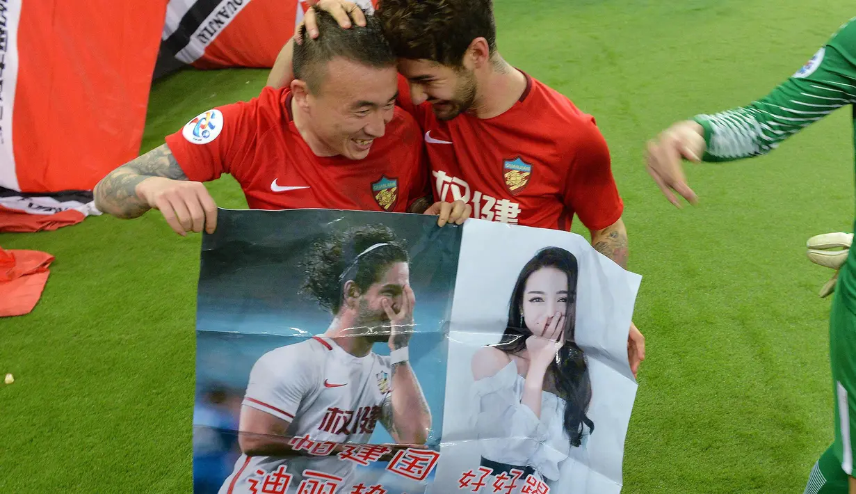 Penyerang Tianjin Quanjian, Alexandre Pato dan rekannya membawa poster aktris Dilraba Dilmurat usai pertandingan melawan South Hyundai Jeonbuk di Liga Champions AFC  di Tianjin (14/3). Poster tersebut tidak diketahui siapa yang buat. (AFP Photo)