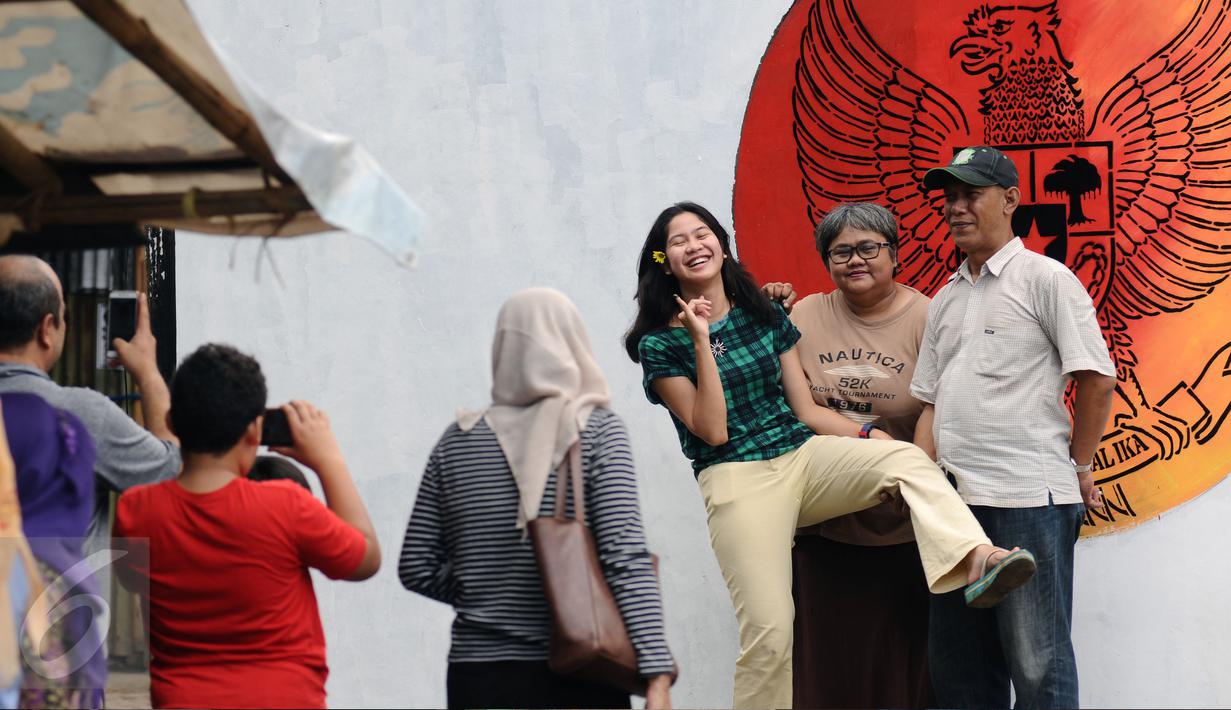 Warga berfoto di depan gambar Garuda Pancasila di Lapangan Kebagusan, Jakarta, Rabu (15/2). Jelang menggunakan hak pilihnya pada Pilkada, Ketua Umum PDI-P Megawati Soekarnoputri menggoreskan tinta pada salah satu gambar. (Liputan6.com/Helmi Fithriansyah)