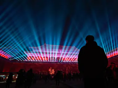 Pengunjung menyaksikan dinding gerbang utama Wu Men Kota Terlarang atau Forbidden City  yang diterangi pertunjukan cahaya selama perayaan Festival Lentera di Beijing, Selasa (19/2). Festival itu menandai berakhirnya liburan Tahun Baru Imlek (AP/Andy Wong)
