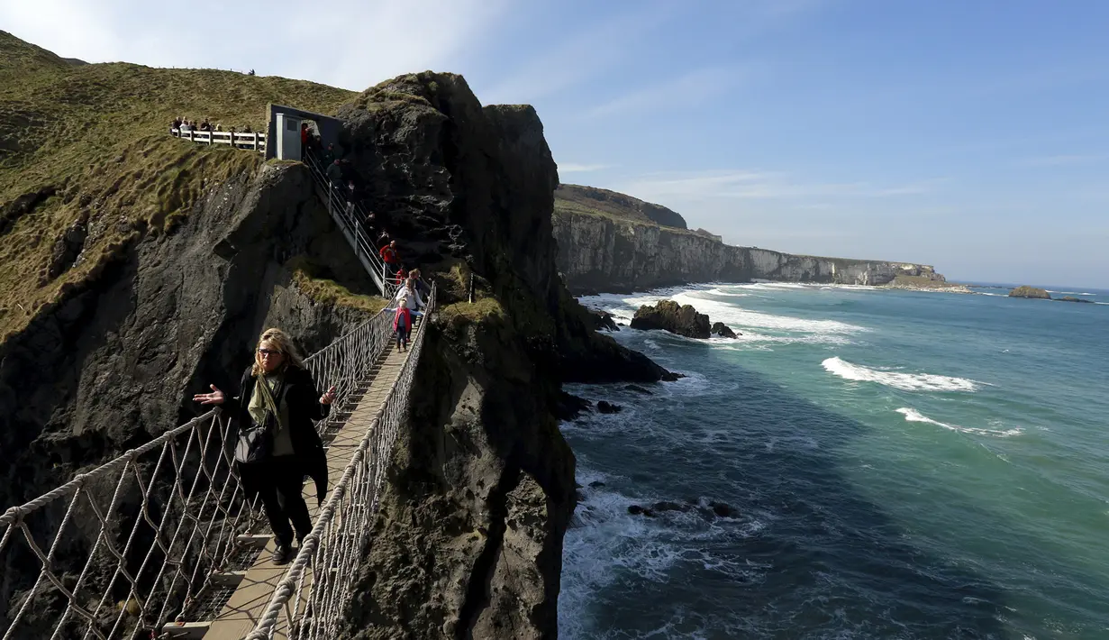 Seorang turis melintasi Jembatan Carrick-a-Rede Rope di Pantai Causeway, Irlandia Utara, Rabu (8/4/2015). Jembatan tersebut diperkirakan telah dibangun selama lebih dari 350 tahun oleh para nelayan salmon. (REUTERS/Cathal McNaughton)
