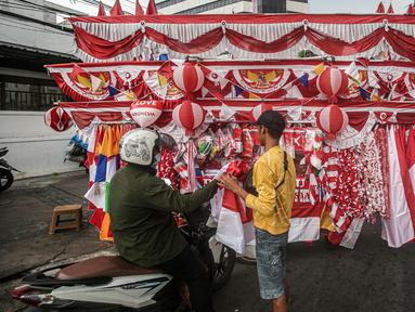 Seorang pedagang bendera merapikan umbul-umbul dan bendera yang di jual di Sepanjang Jalan Jatinegara, Jakarta, Selasa (2/8/2022). Jelang peringatan HUT Kemerdekaan RI ke-77, pedagang musiman bendera  mulai bermunculan mereka memanfaatkan trotoar untuk memajang dagangannya, mulai dari umbul-umbul, bendera, hingga ornamen khas merah putih lainnya dengan harga yang tawarkan juga bervariasi, mulai dari Rp. 5.000 ,- hingga Rp. 300.000,. (Liputan6.com/Faizal Fanani)