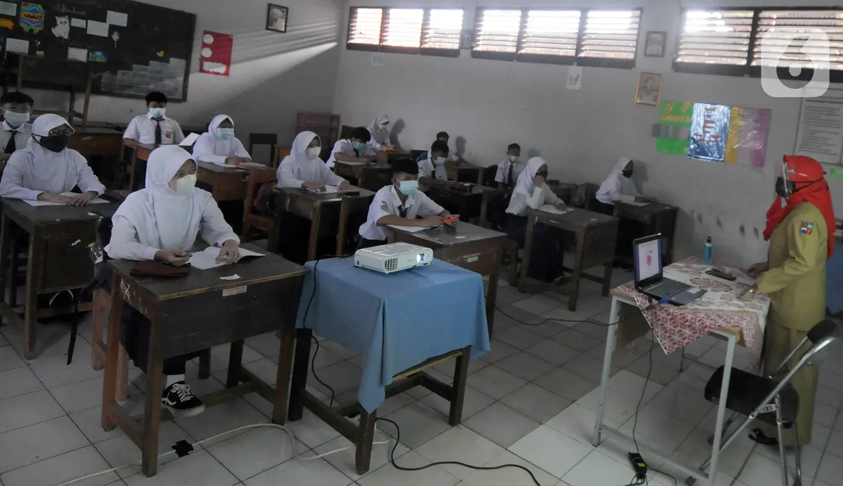 Guru mengajar para murid saat pelaksanaan uji coba pendidikan tatap muka (PTM) di SMPN 15, Kota Bogor, Jawa Barat, Senin (31/5/2021). Pemerintah Kota Bogor menggelar uji coba PTM di 37 sekolah hari ini dengan protokol kesehatan yang ketat. (merdeka.com/Arie Basuki)