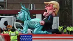 Sebuah patung berbentuk menyerupai Patung Liberty dan Presiden AS ikut dalam karnaval tradisional 'Rose Monday' di Dusseldorf, Jerman Barat, Senin (27/2). Karnaval 'Rose Monday' berisi sindiran satir para pemimpin dunia. (AFP PHOTO / Patrik STOLLARZ)