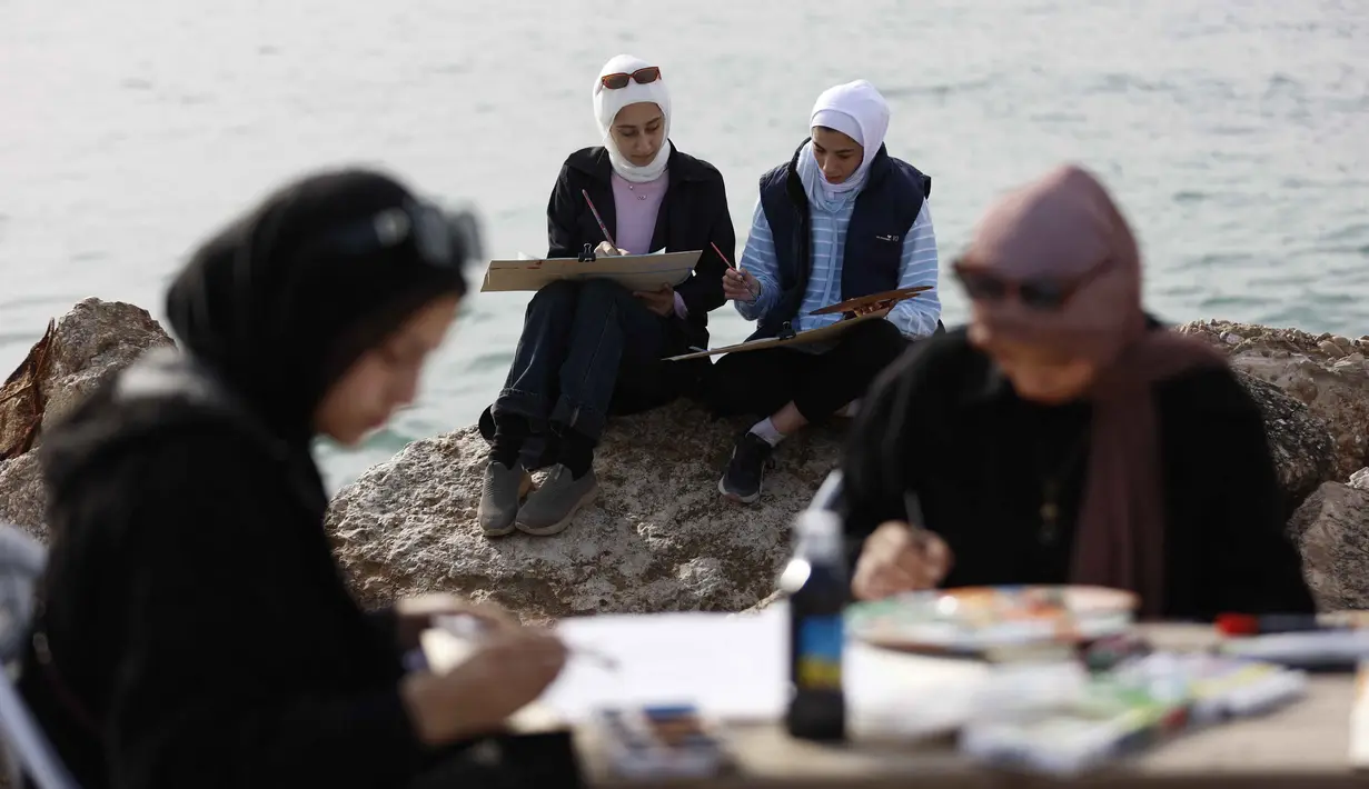 Lokakarya Bernapas dan Melukis menjadikan seni sebagai bentuk perlawanan dan sarana bertahan hidup di tengah krisis akibat perang. Tampak dalam foto, Para perempuan muda melukis di pelabuhan Kota Gaza pada Kamis 12 Februari 2026. (Omar AL-QATTAA/AFP)