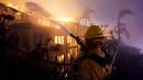 Seorang petugas pemadam kebakaran bekerja untuk memadamkan sebuah bangunan yang terbakar saat kebakaran hutan di Laguna Niguel, California, Amerika Serikat, 11 Mei 2022. (AP Photo/Marcio J. Sanchez)
