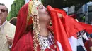 Seorang perempuan yang mengenakan kostum tradisional mencium bendera nasional Tunisia dalam perayaan tahunan Hari Perempuan Nasional di pusat kota Tunis, Tunisia, pada 13 Agustus 2020. (Xinhua/Adel Ezzine)