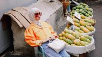 Pasar dengan deretan buah mangga menjadi salah satu lokasi pemotretan Tantri Namirah. Ibu satu anak ini tampil senada dengan blazer bewarna oren dan kacamata yang membuat penampilan semakin trendi. (Liputan6.com/IG/@tantrinamirah)