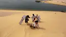 Sejumlah pengunjung menaiki gurun setelah turun berseluncur di gurun pasir Wadi el-Rayan Fayoum, Mesir (18/11). Sandboarding ini hampir sama dengan snowboarding, yang membedakan adalah medannya yakni di pasir. (Reuters/Mohamed Abd El Ghany)
