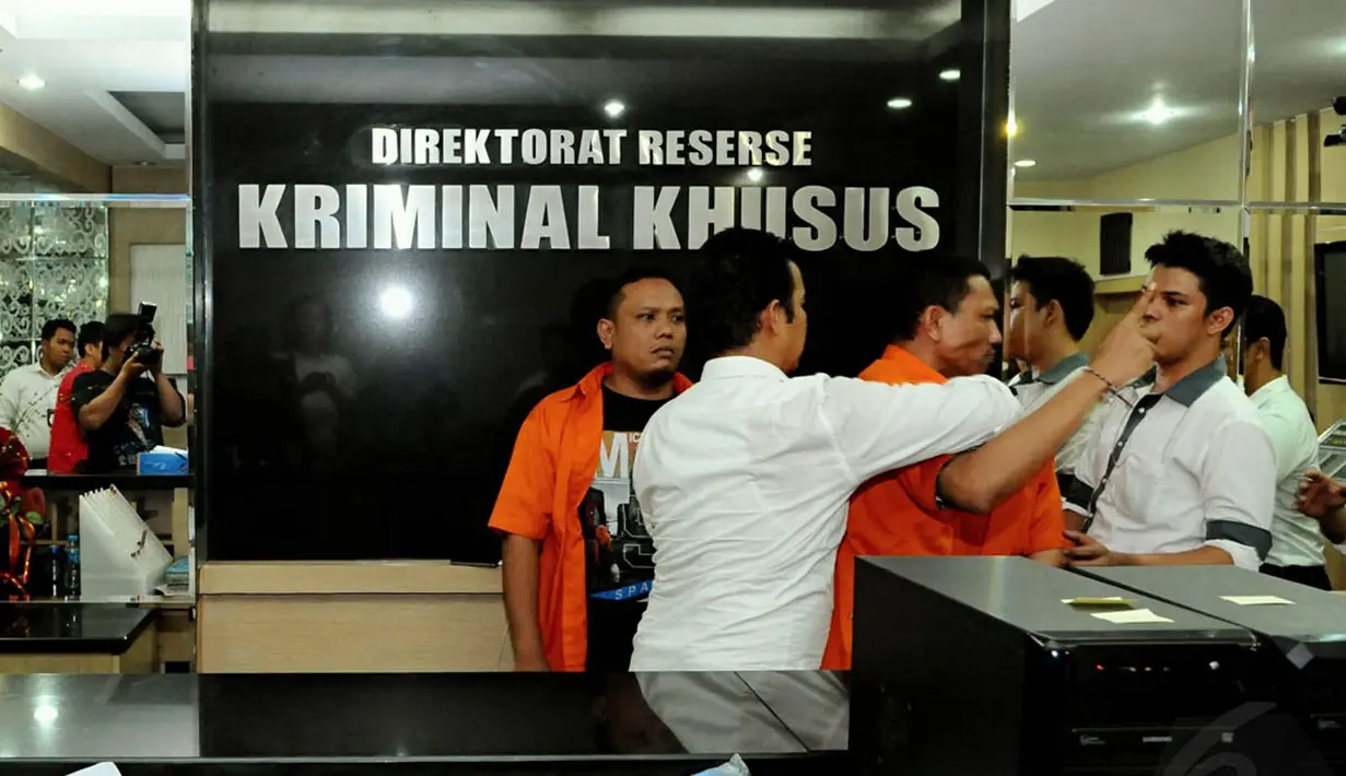 Petugas kepolisian menggiring masuk tersangka kasus pemerasan, Raden Nuh, yang berteriak saat digelar rilis di Mapolda Metro Jaya, Jakarta, Senin (3/11/2014). (Liputan6.com/Andrian M Tunay)