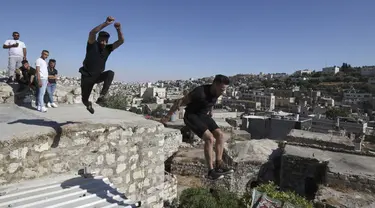 Pemuda Palestina Hammam Abu Sneineh (kiri) dan Abdallah al-Natsheh berlatih parkour di atas atap dan tangga rumah batu tradisional di Kota Hebron, Tepi Barat, Sabtu (5/6/2021). (HAZEM BADER/AFP)