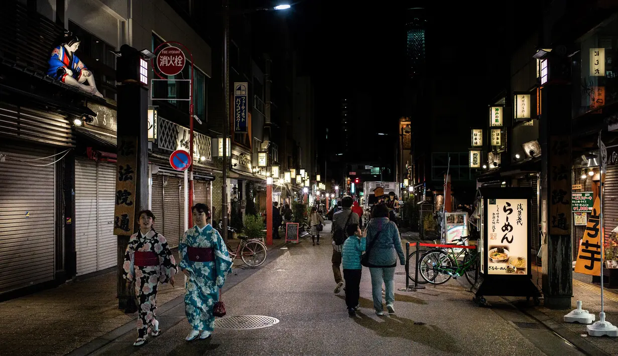 Dua wanita mengenakan kimono berjalan di jalan daerah Asakusa di Tokyo (1/12). Asakusa terletak di pinggir utara-timur pusat bandar Tokyo, di hujung timur Subway line Ginza. (AFP Photo/Martin Bureau)