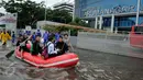 Warga menggunakan perahu karet melintasi banjir yang merendam Jalan S Parman, di depan Universitas Tarumanagara (Untar), Jakarta, Selasa (21/2). Banjir di kawasan ini disebabkan meluapnya beberapa sungai di Jakarta Barat. (Liputan6.com/Gempur M Surya)